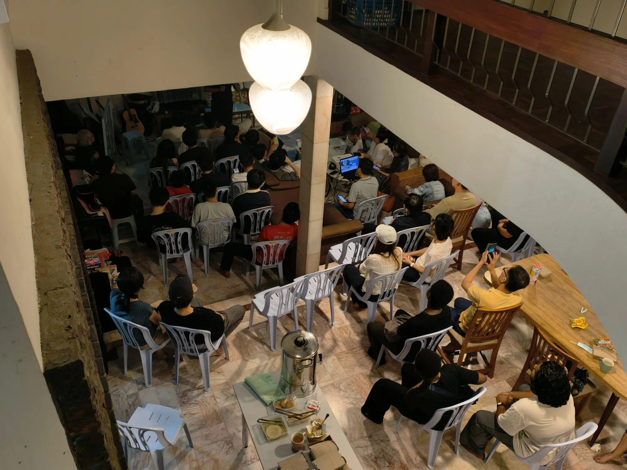 A large group of students and volunteers gathered at DU House, seen from the floor above
