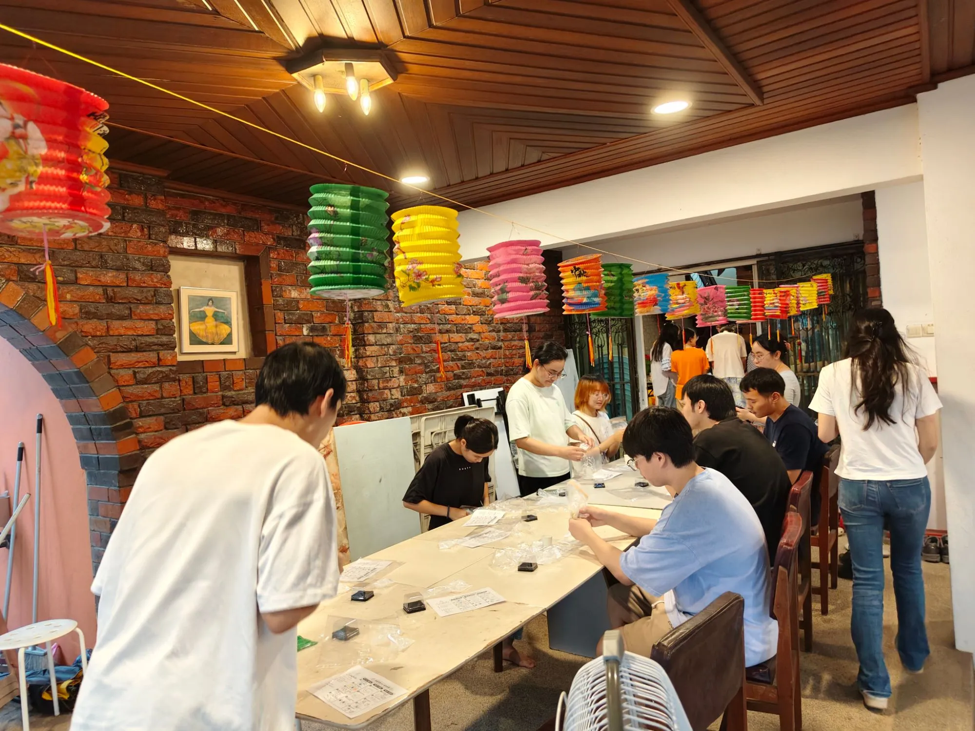 Students gathered around a long table at DU House, under strings of colourful paper lanterns